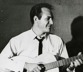 Fred Carter Jr. strums a guitar and smiles off to the viewer's right