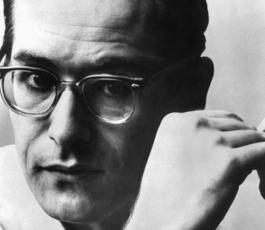 A portrait Bill Evans, wearing glasses and holding a cigarette