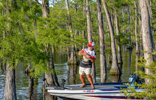 A man fishes from a boat in the bayou