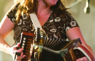 A woman playing an accordion on stage at the Festival Acadiens et Creoles in Lafayette.