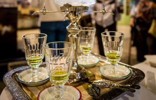 An ornate tray holds three cups with a few ounces of absinthe, a bright green liquid, at La Galerie de l'Absinthe at the Southern Food &amp; Beverage Museum.